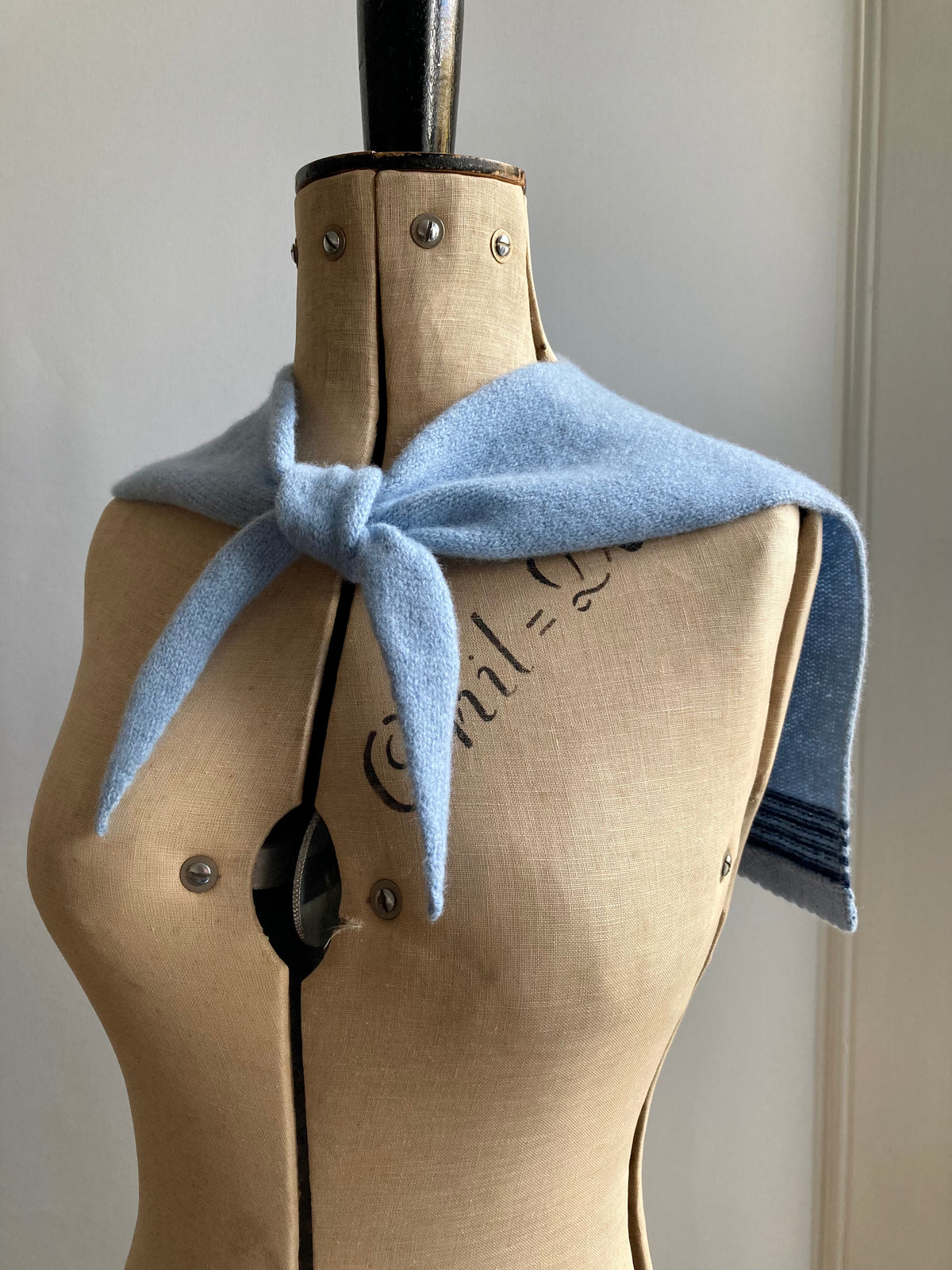 Mannequin wearing a light blue sailor collar scarf with dark blue stripes.