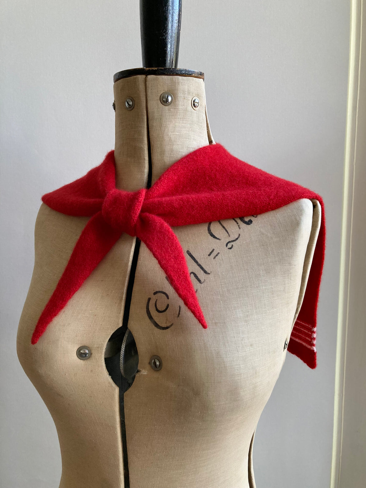 Knitted red sailor scarf with pale pink stripes styled on a mannequin.