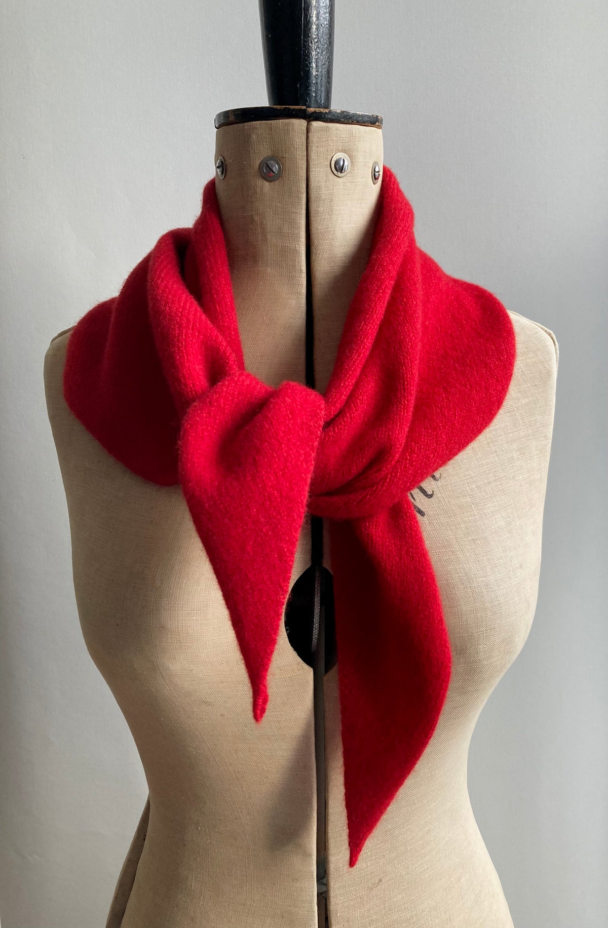 A bright red wool larger neck scarf styled on a mannequin.