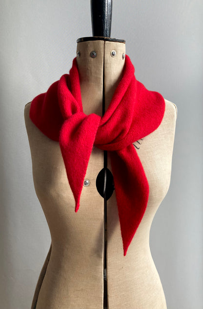 A bright red knitted larger neck scarf styled on a beige fabric mannequin.