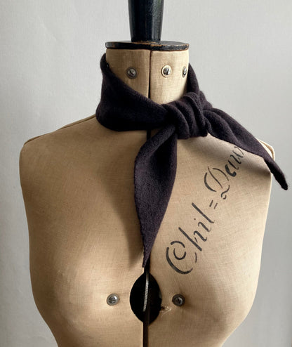 A dark brown knitted thin neck scarf tied around a mannequin.