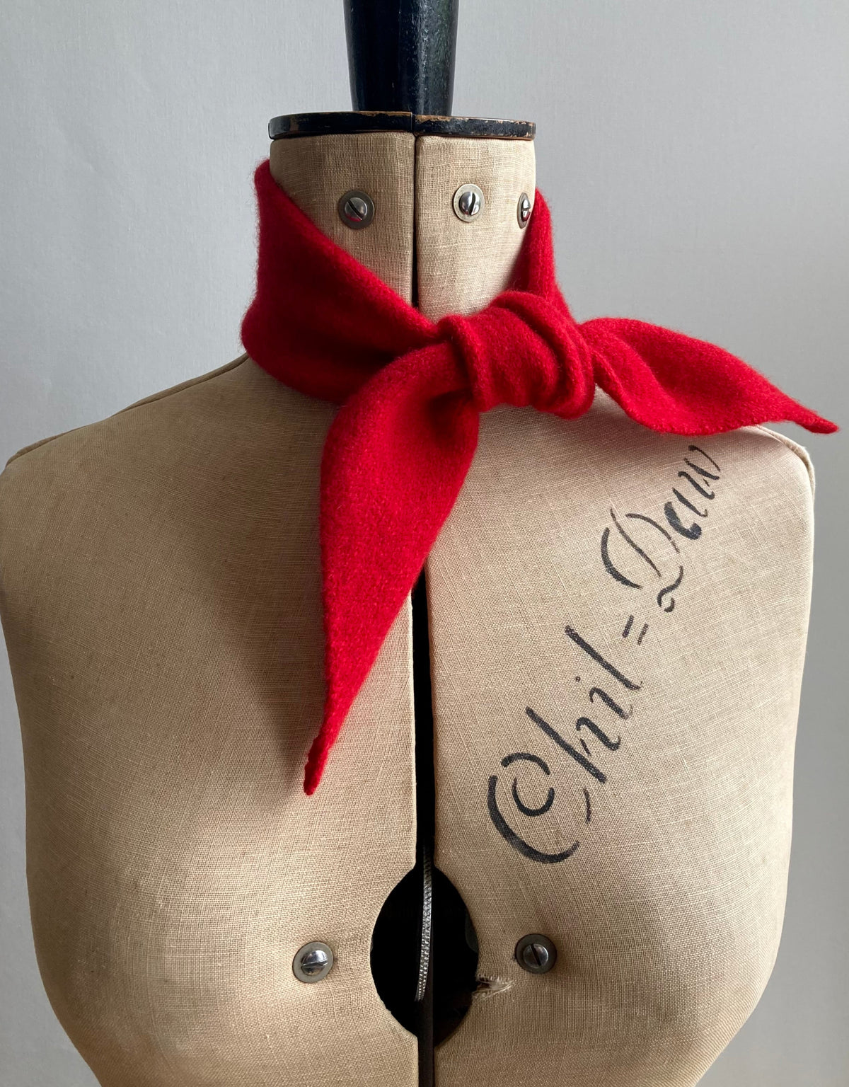 A bright red thin bandana tied around the neck of a mannequin.