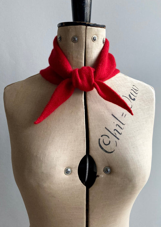 A bright red mini bandana scarf tied in a knot on a mannequin.