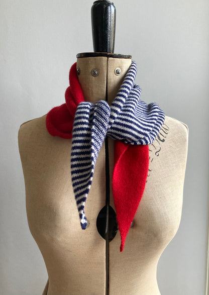 A scarf displayed on a mannequin. The neckerchief is knitted half red and half navy and white stripes.