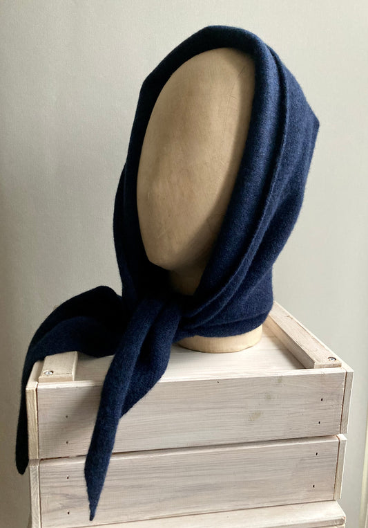 A navy blue hooded scarf displayed on a head shaped mannequin.